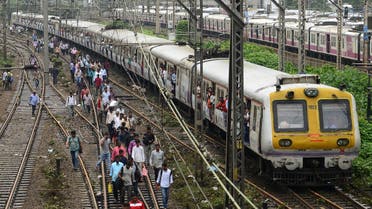 Indian commuters walk on railway tracks as train services slowly resume in Mumbai on August 30, 2017, after heavy rains brought major flooding to the coastal city. (AFP)