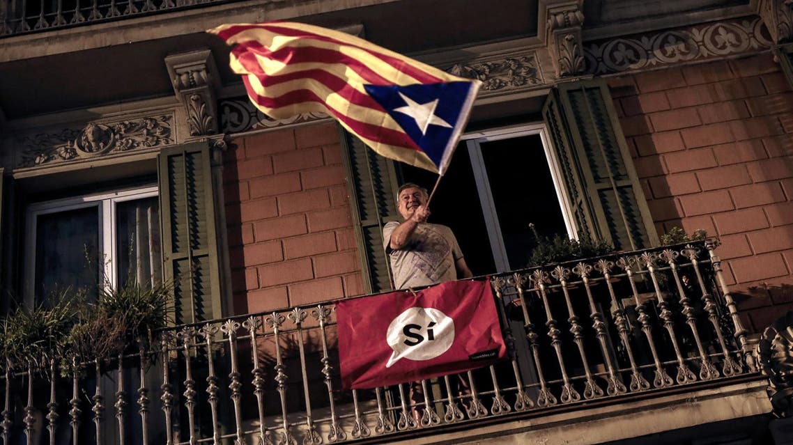 A man waves an ‘Estelada’ (Pro-independence Catalan flag) from a balcony after the closing of the La Fontana youth center polling station, on October 1, 2017 in Barcelona. (AFP)