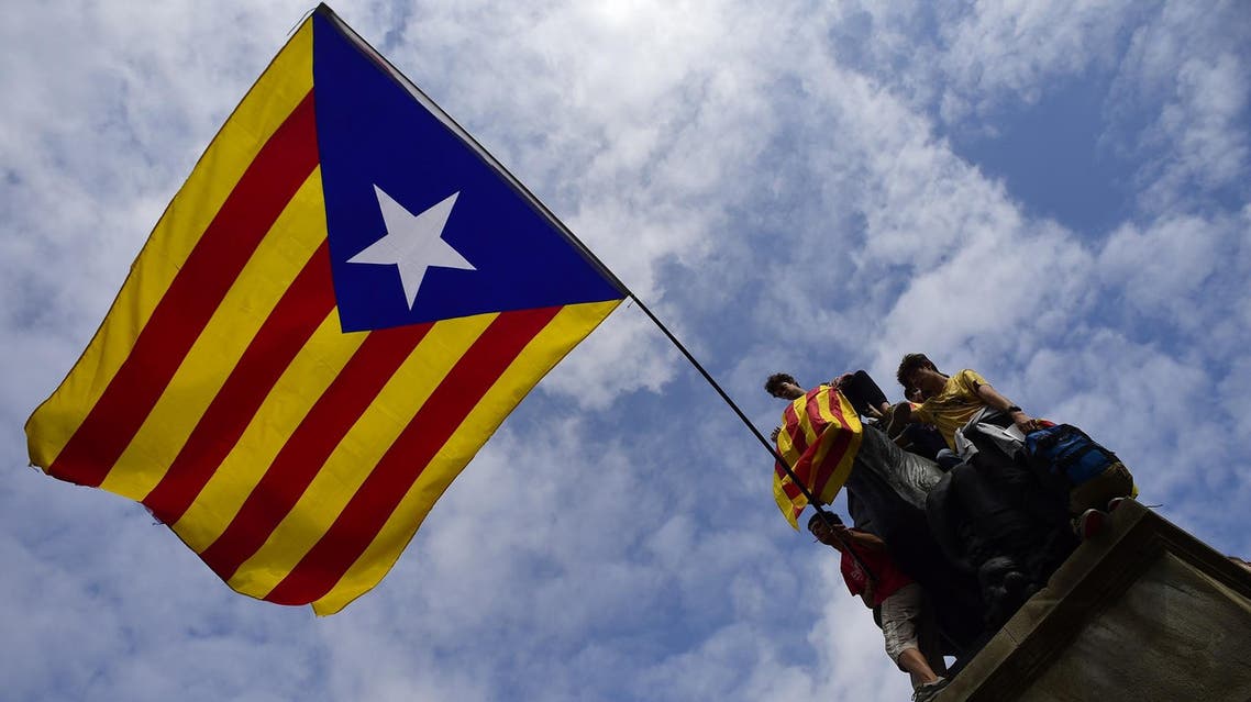 Protesters wave a giant Catalan pro-independence ‘Estelada’ flag atop a sculpture during a demonstration in Barcelona on October 2, 2017. (AFP)