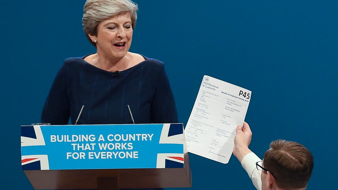 Protester comedian Simon Brodkin (R) gives a piece of paper written as a mock P45 (employee leaving form) to Britain's Prime Minister Theresa May (L) as she was delivering her speech on the final day of the Conservative Party annual conference at the Manchester Central Convention Centre in Manchester, northwest England, on October 4, 2017.afp