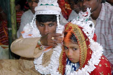 An Indian groom puts vermilion, the holy mark belived the as sign of hindu marriage, on the forehead of his underage bride during a mass marriage programme in the village of Malda, some 360 Kms. northeast of Kolkata, 02 March 2006. (AFP)