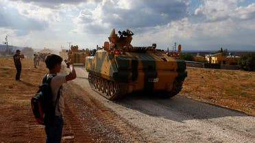 A boy salutes as Turkish army vehicles drive pass by their village on the Turkish-Syrian border line in Reyhanli, Hatay province, Turkey, October 11, 2017. reuters