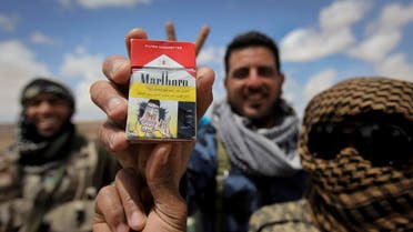 Libyan rebel fighters hold up a packet of cigarettes on which they had put a homemade joke health warning featuring a caricature of Moammar Gadhafi, on the outskirts of Ajdabiya, Libya Monday, April 18, 2011. (AP)