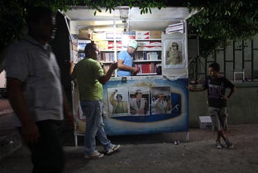 In this photo taken on a government-organized tour, a Libyan man with pictures of Libyan leader Moammar Gadhafi on his stall, sells cigarettes during a protest in Tripoli, Libya, Thursday, July 28, 2011. (AP)