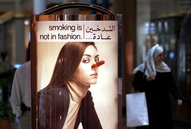 An Arab woman walks behind an anti smoking poster in a Dubai mall September 1, 2004. (Reuters)