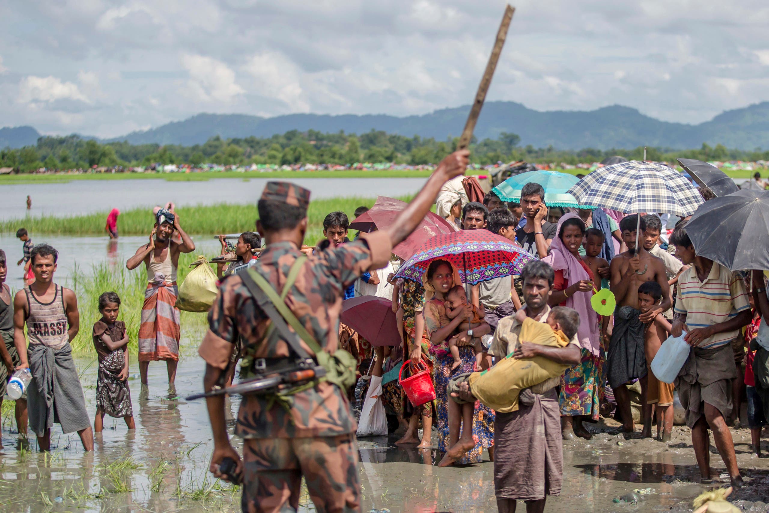 A Bangladesh border guard soldier stops newly arrived Rohingya Muslims, who crossed over from Myanmar into Bangladesh, AP