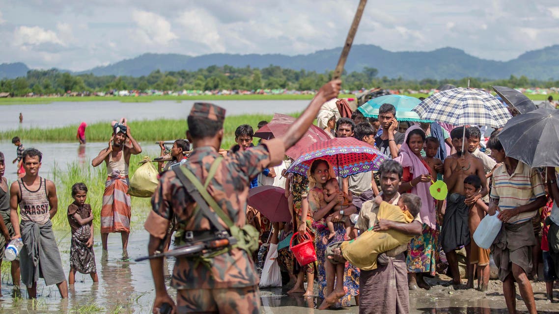 A Bangladesh border guard soldier stops newly arrived Rohingya Muslims, who crossed over from Myanmar into Bangladesh, AP
