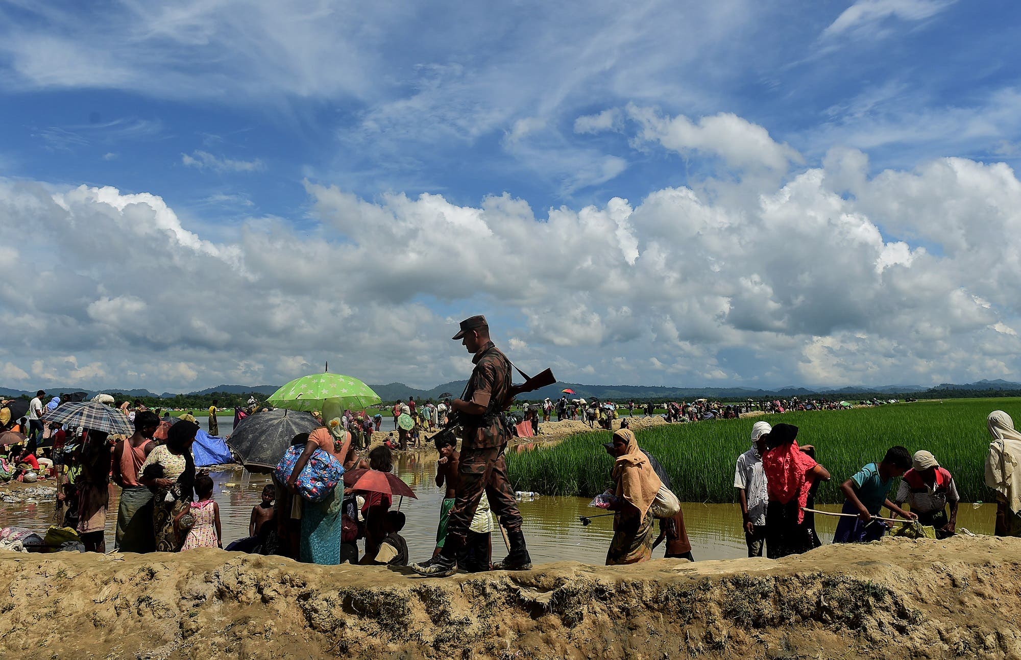 A Bangladesh border guard walks amongst Rohingya refugees walking in an area near no man’s land on the Bangladesh side of the border with Myanmar after crossing the Naf River on October 17, 2017. (AFP)