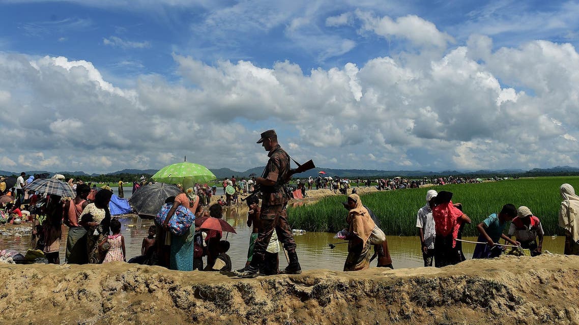 A Bangladesh border guard walks amongst Rohingya refugees walking in an area near no man’s land on the Bangladesh side of the border with Myanmar after crossing the Naf River on October 17, 2017. (AFP)