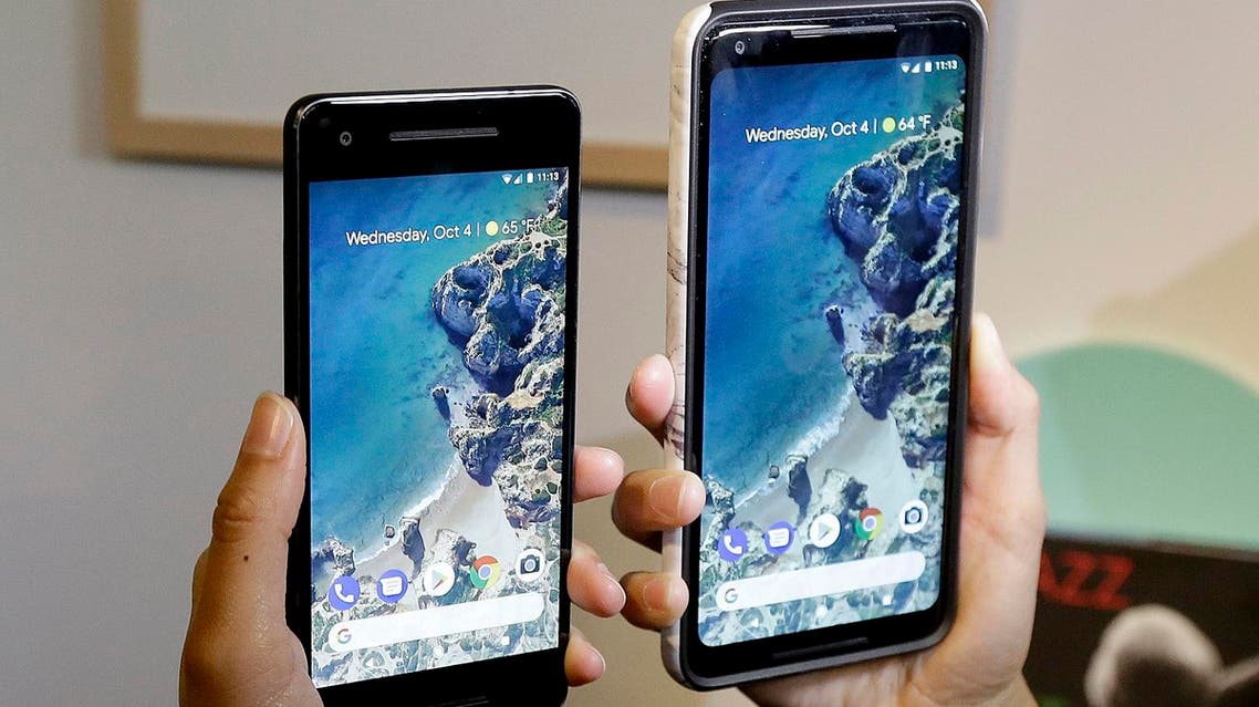 FILE - In this Wednesday, Oct. 4, 2017, file photo, a woman holds up the Google Pixel 2 phone, left, next to the Pixel 2 XL phone at a Google event at the SFJAZZ Center in San Francisco. The phones set themselves apart with promises to bake in Google’s powerful artificial-intelligence technology for quick and easy access to useful, even essential information. You get some of that right away, but more will come later through free software updates and a wireless accessory. (AP Photo/Jeff Chiu, File)