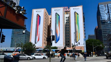 A skateboarder jumps the curb crossing a street in Los Angeles, California on october 13, 2017, where advertising for Apple's new iPhone X, due for release on November 3, covers the sides of three highrise buildings. (AFP)