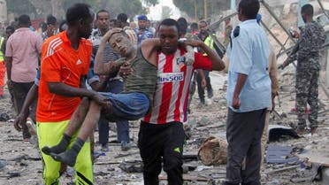 Civilians assist a man injured from a suicide car bombing at the gate of Naso Hablod Two Hotel in Mogadishu. (Reuters)