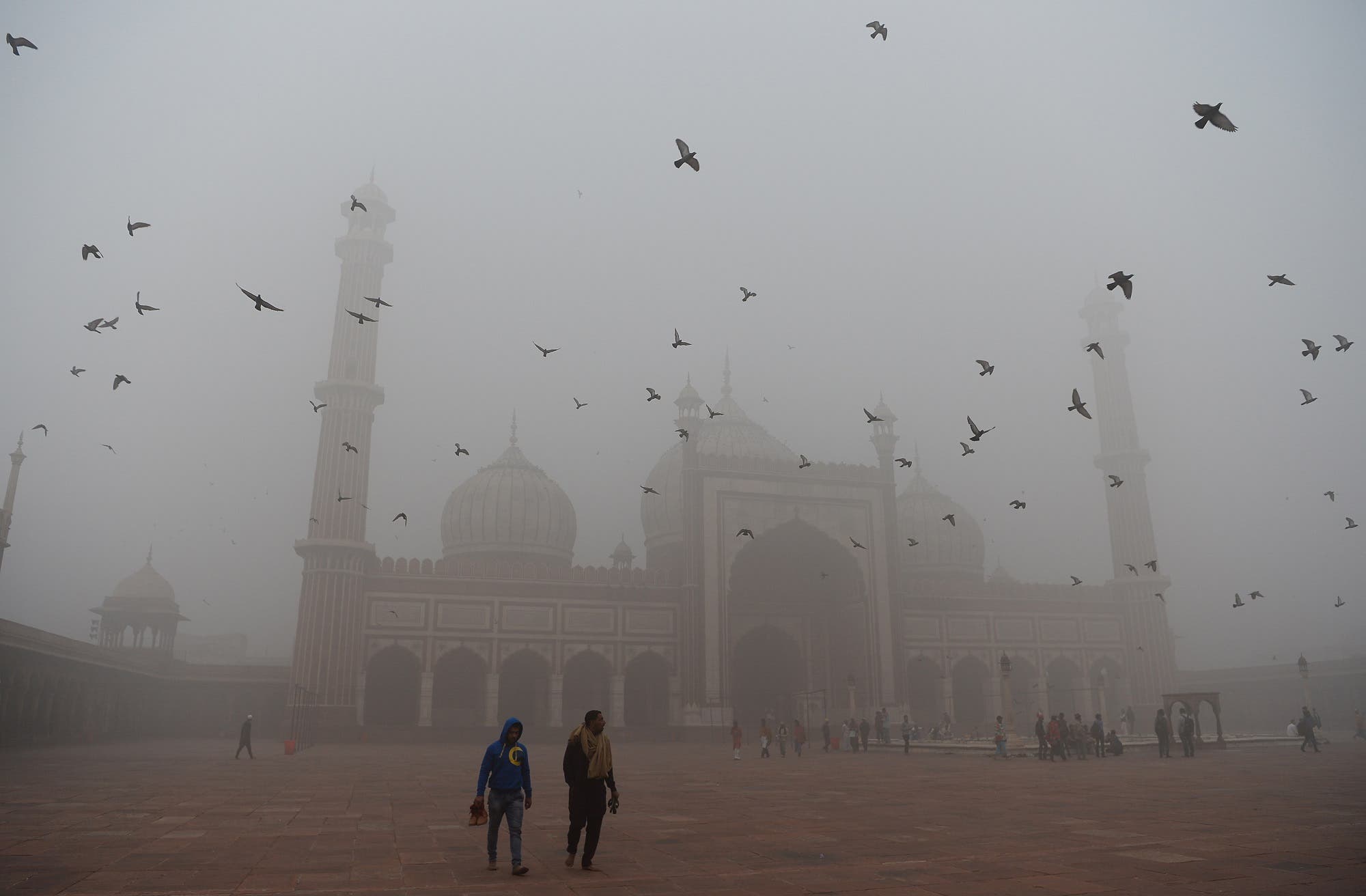 Indian visitors walk through the courtyard of Jama Masjid amid heavy smog in the old quarters of New Delhi on November 8, 2017. (AFP)