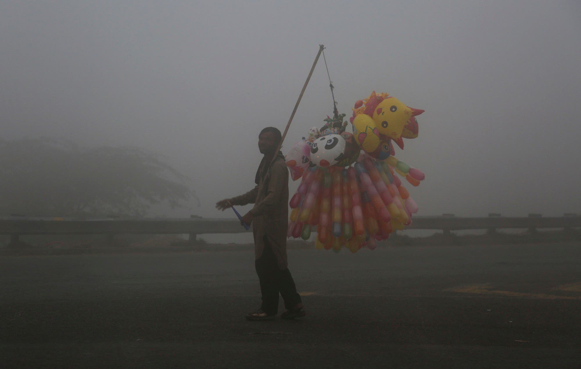 A Pakistani vendor sells balloons while fog envelopes the area in Lahore, Pakistan, on Nov. 8, 2017. (AP)