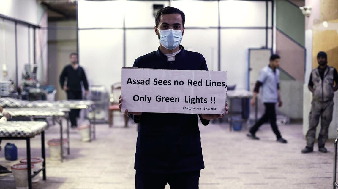 A medical staff at a hospital holds a placard condemning a suspected chemical weapons attack on Khan Sheikhun on the outskirts of Damascus on April 6, 2017. (AFP)