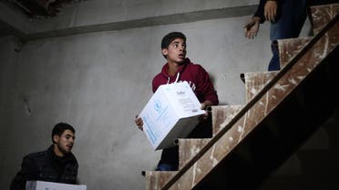 Syrian youths unload humanitarian aid parcels from a Syrian Red Crescent truck in the besieged rebel-held Eastern Ghouta region outside Damascus on October 30, 2017. The joint UN-Syrian Arab Red Crescent convoy included 49 trucks carrying "eight thousand food parcels and a similar number of bags of flour, medicine, medical supplies, and other nutritional materials," Red Crescent spokeswoman Mona Kurdi said. (AFP)