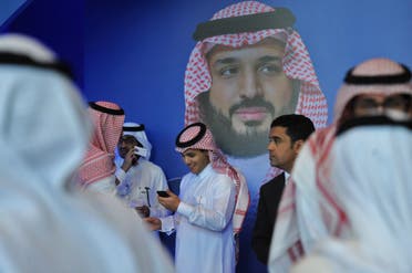 Saudi men chat in front of a poster of Saudi Crown Prince Mohammed bin Salman during the MiSK Global Forum in Riyadh, on November 15, 2017. (AFP)