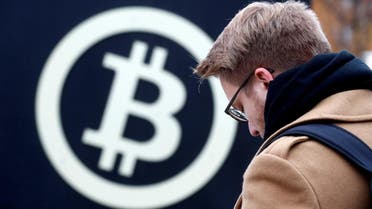 A man stands next to the bitcoin sign during Riga Comm 2017, a business technology and innovation fair in Riga, Latvia November 9, 2017. (Reuters)