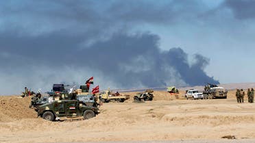 Smoke rises from the Ajil oil field as Shi’ite fighters stand near their vehicles in Al Hadidiya, where they were preparing to launch an offensive on March 6, 2015. (Reuters)