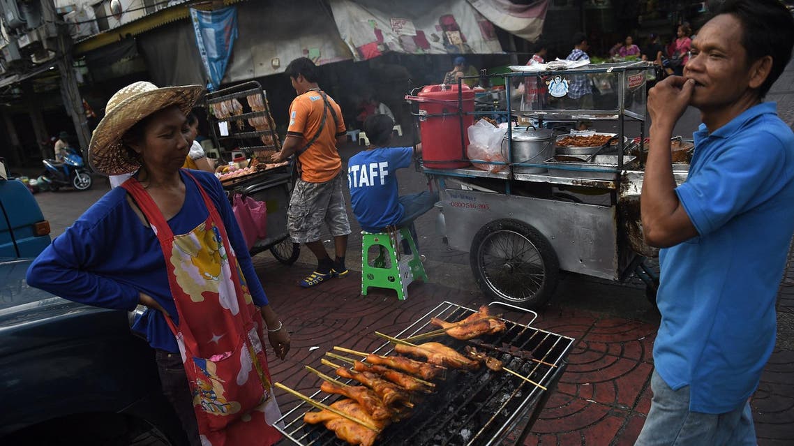This April 12, 2016 picture shows food vendors preparing chicken at their street stall in Bangkok’s Chinatown. (AFP)