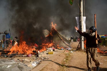 A protester walks near burning tents during clashes with police at Faizabad junction in Islamabad. (Reuters)