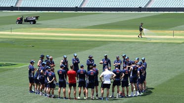 A groundsman sprays water on the pitch as England cricket team players and coaching staff stand in a circle during a training session at the Adelaide Oval. (Reuters)