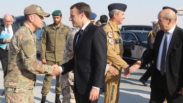 French President Emmanuel Macron (C) greets a US army commander near Foreign Minister Jean-Yves Le Drian (R) upon their arrival in the Qatari capital Doha on December 7 2017. KARIM JAAFAR / AFP    