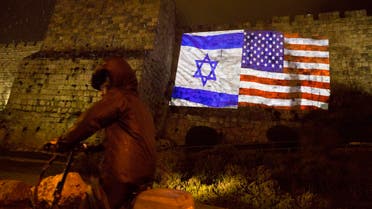 An ultra Orthodox Jewish man rides a bicycle as US and Israeli flags are projected on the walls of Jerusalem’s old city, Wednesday, Dec. 6, 2017. (AP)