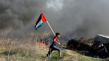 A protester holds a Palestinian flag as he runs during clashes with Israeli troops as Palestinians call for a "day of rage" in response to U.S. President Donald Trump's recognition of Jerusalem as Israel's capital, near the border with Israel in the east of Gaza City December 8, 2017. REUTERS/Mohammed Salem