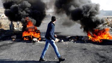 A Palestinian protester walks in front of a burned barricade during a protest near the Jewish settlement of Beit El on December 14, 2017. (Reuters)