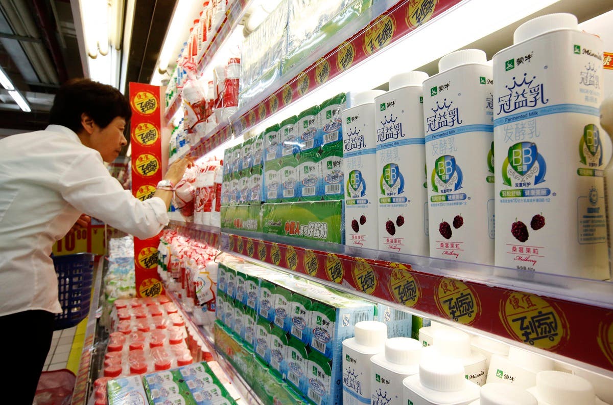 A customer shops near Mengniu's dairy products (R) displayed on shelves at a supermarket in Beijing June 19, 2013. (Reuters)