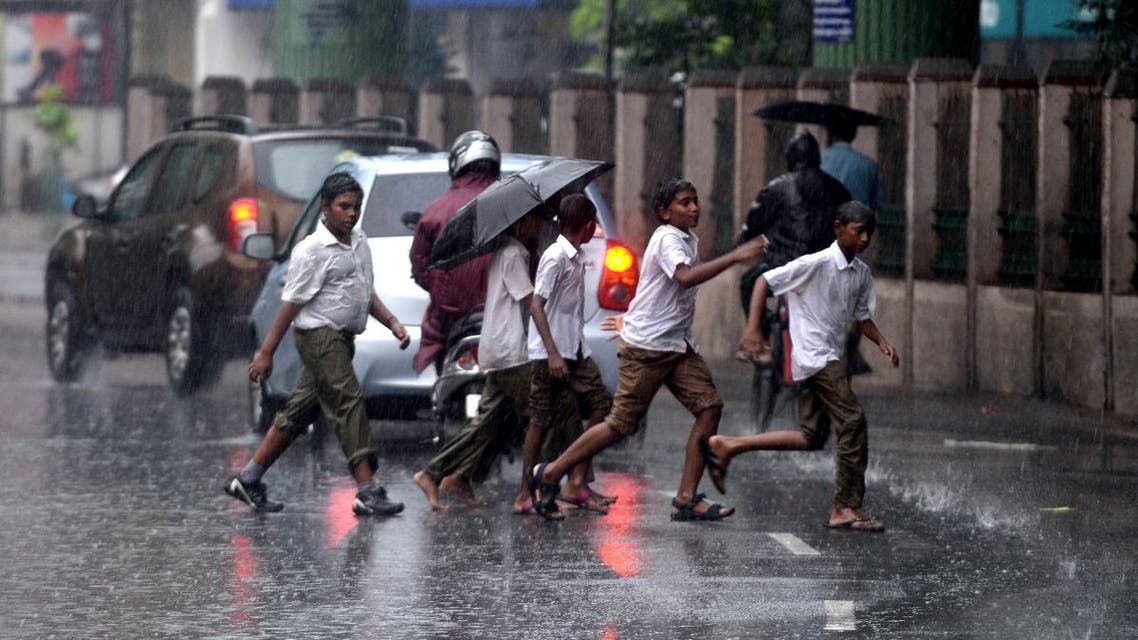 Indian school students run along a street under monsoon rains in Chennai on October 30, 2017. (AFP)
