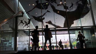 People are silhouetted as they enter a subway station where the glass entrance is decorated with decals of athletes in action in Singapore. (AP)