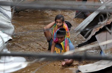 A policeman carries a young girl as he wades through a flooded street in Cagayan City. (AFP)