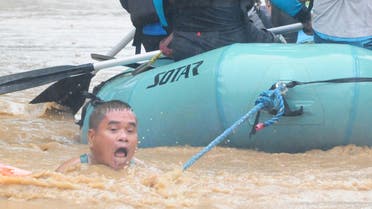 A man clings onto the rope of a rescue boat as residents are evacuated from their homes. (Reuters)