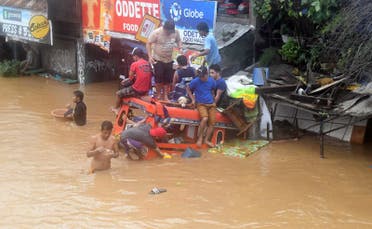 Residents are seen on the top of a partially submerged vehicle along a flooded road in Cagayan de Oro city in the Philippines December 22, 2017. (Reuters)