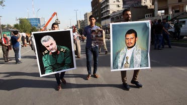 An Iraqi holds a portrait of Shiite Huthi rebels' leader in Yemen, Abdulmalik al-Huthi (R) and General Qassem Suleimani (L), the commander of the Quds Force, the foreign operations arm of Iran's Revolutionary Guards. (AFP)