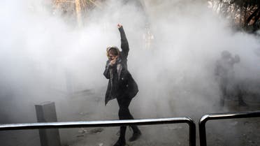 An Iranian woman raises her fist amid the smoke of tear gas at the University of Tehran during a protest driven by anger over economic problems, in Tehran on December 30, 2017. (AFP)
