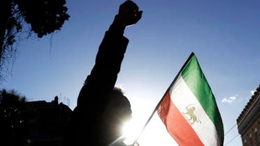 A demonstrator shouts slogans near the flag of the former Imperial State of Iran. (AP)