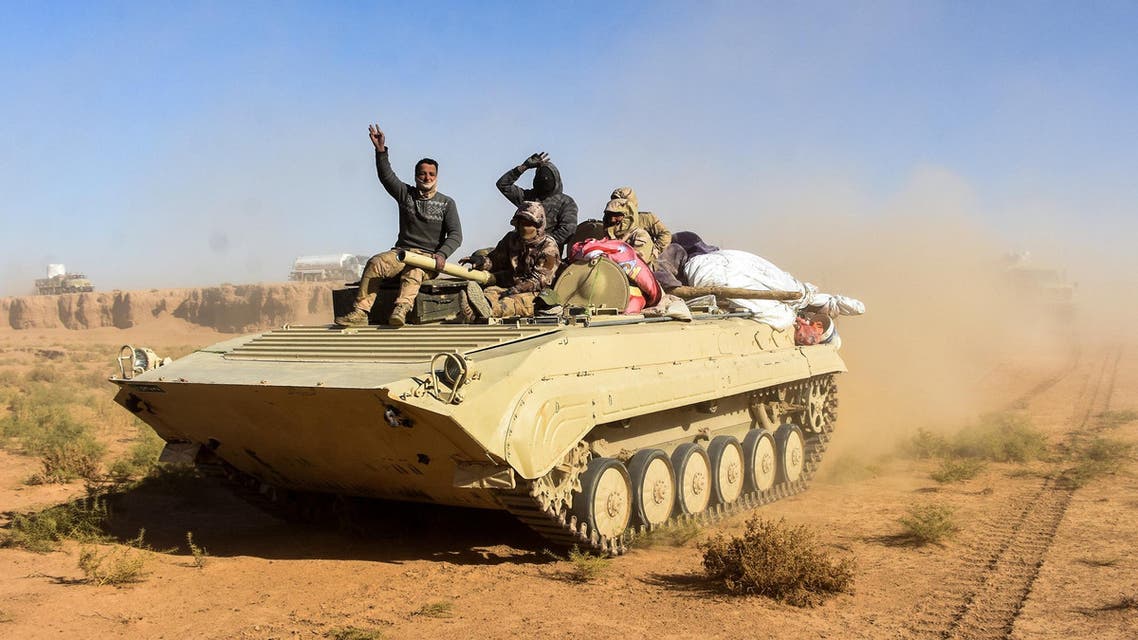 Members of the Iraqi forces and the Hashed al-Shaabi (Popular Mobilisation units) wave as they ride on an infanty-fighting vehicle (IFV) near the Iraqi-Syrian border, about 80 kilometres (about 50 miles) west of the border town of al-Qaim on December 9, 2017. STRINGER / AFP