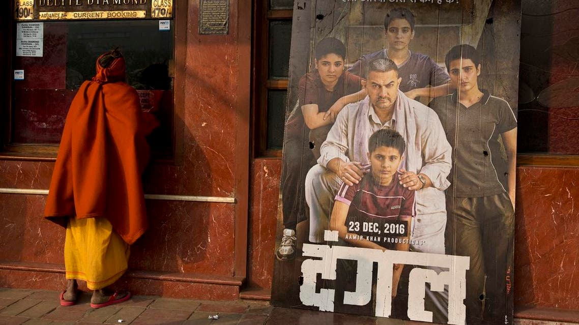 An Indian Sadhu, or Hindu holy man, buys a movie ticket at a counter beside a poster of Bollywood movie Dangal. (AP)