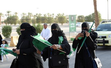 Saudi women carry national flags as they arrive outside a stadium for the first time to attend an event in the capital Riyadh on September 23, 2017. (AFP)