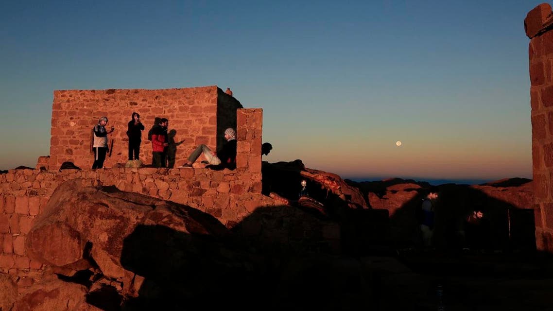 Arab tourists, left and American tourists, right, watch the sun as it rises and the moon as it sets from the view on top Mount Sinai. (AP)