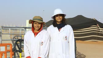 What are two Indian girls doing at the camel festival in Riyadh?
