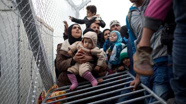 A Syrian family wait along the wire fence that separates the Greek side from the Macedonian one. (AP)