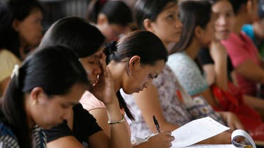 A woman fills an application form for a job posting in Kuwait during a job fair in Manila on September 20, 2010. (Reuters)
