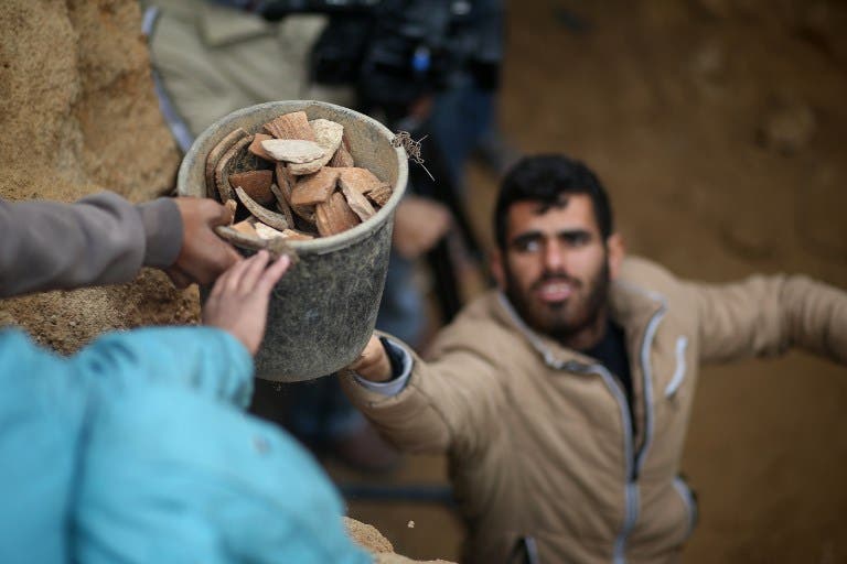 Abdul Karim al-Kafarnah, a Palestinian resident of Beit Hanun, passes on a bucket full of pottery fragments at a freshly-discovered cemetery in the garden of his house in the town in the northern Gaza Strip, on January 26, 2018. Experts said the graves were part of a loculus tomb that possibly dates from the late Roman-Byzantine era in the fourth to sixth century CE. MOHAMMED ABED / AFP