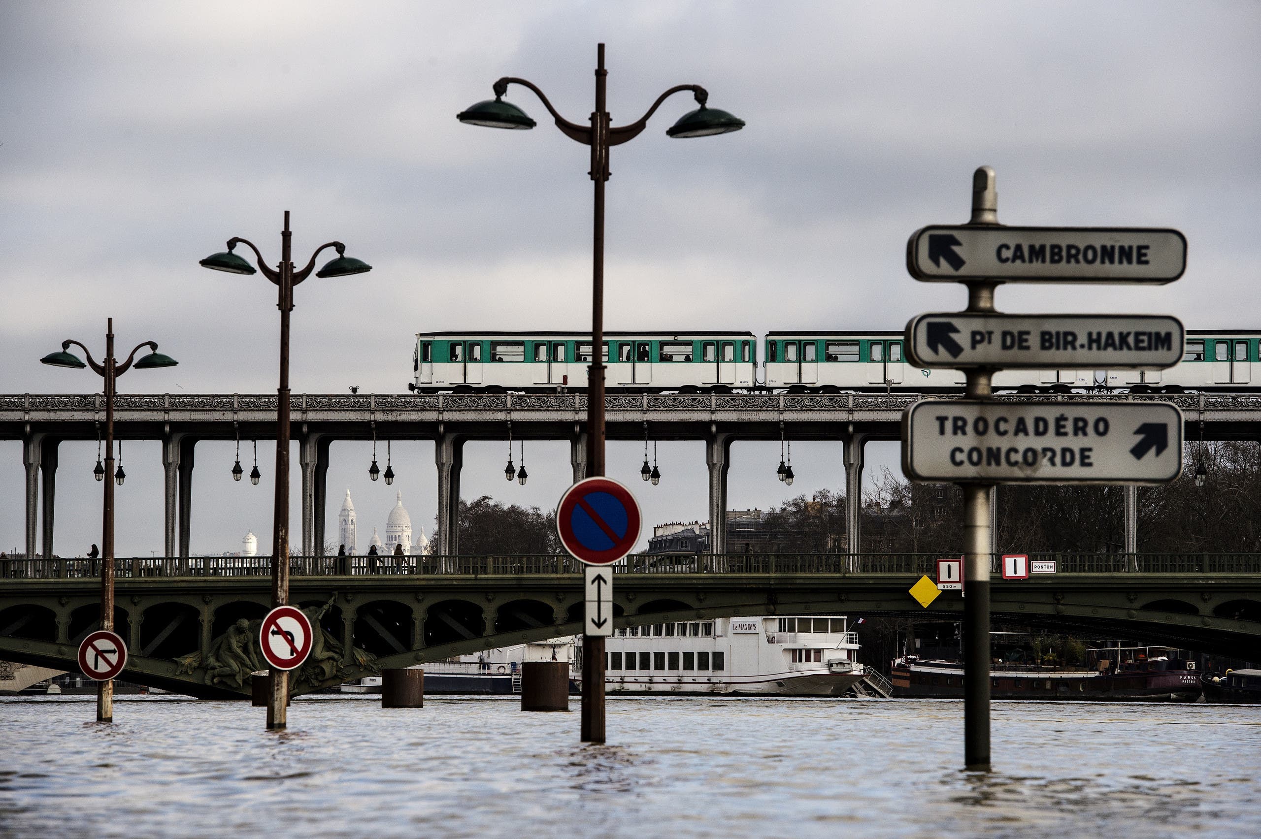 Pedestrians and a metro train cross the swollen Seine river on the Bir-Hakeim bridge in Paris on January 26, 2018. (AFP)