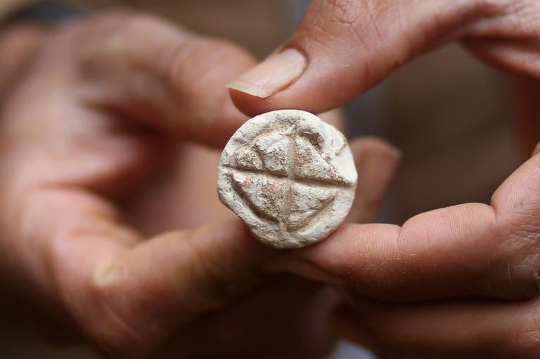 Abdul Karim al-Kafarnah, a Palestinian resident of Beit Hanun, holds a seal at a freshly-discovered cemetery in the garden of his house in the town in the northern Gaza Strip, on January 26, 2018. Experts said the graves were part of a loculus tomb that possibly dates from the late Roman-Byzantine era in the fourth to sixth century CE. MOHAMMED ABED / AFP