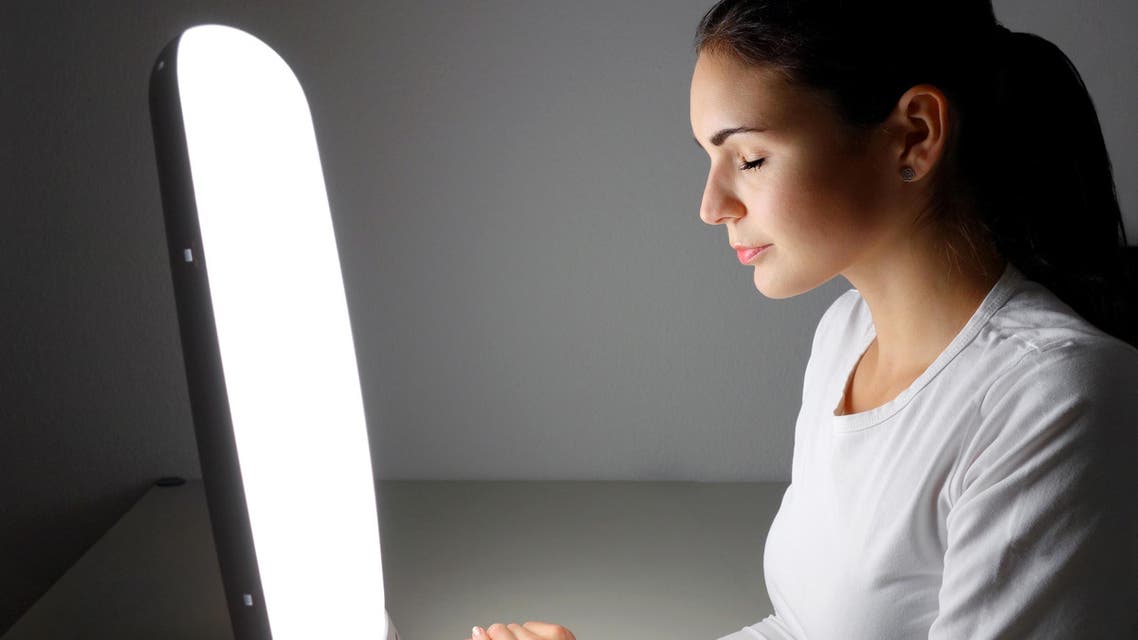 Young woman administering a light therapy agains winter depression - Stock image...